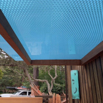 clear-PEP ECO panels in clear blue and satin opal white, complementing a wooden residence with elegant awnings and canopies MoxieSurfaces - clear-PEP ECO panels - Digigloramo Residence