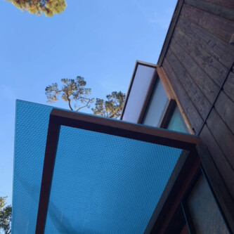 clear-PEP ECO panels in clear blue and satin opal white, complementing a wooden residence with elegant awnings and canopies MoxieSurfaces - clear-PEP ECO panels - Digigloramo Residence